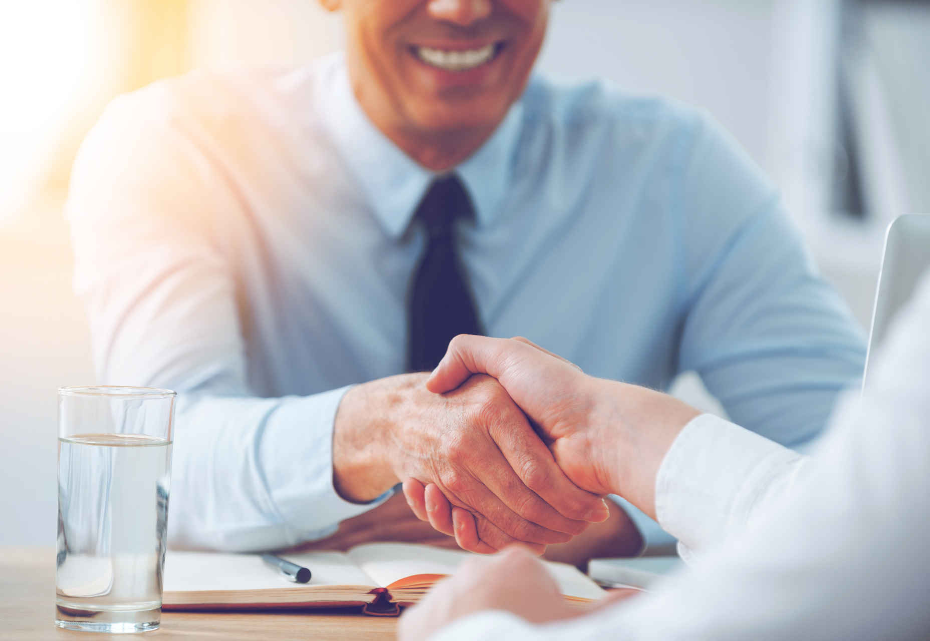 Good deal. Close-up of two business people shaking hands while sitting at the working place